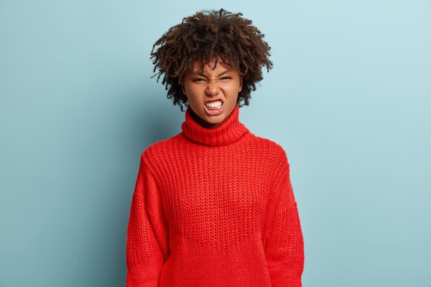 Mujer joven con corte de pelo afro vistiendo suéter rojo