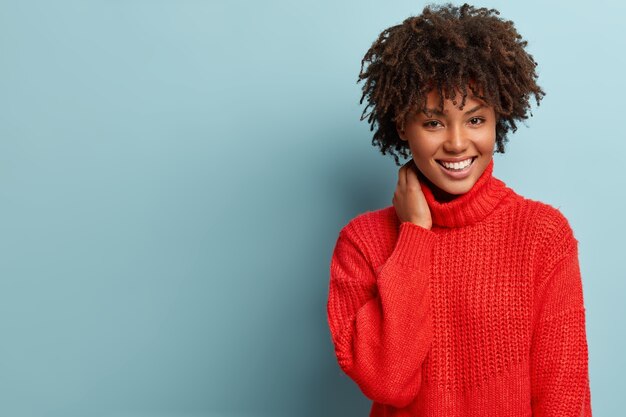 Mujer joven con corte de pelo afro vistiendo suéter rojo