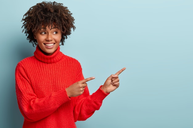 Mujer joven con corte de pelo afro vistiendo suéter rojo