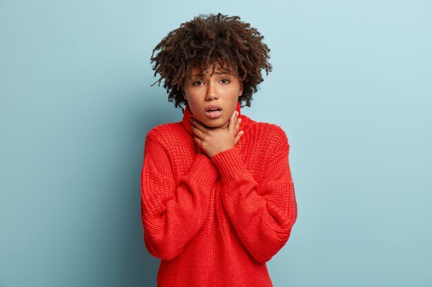 Mujer joven con corte de pelo afro vistiendo suéter rojo