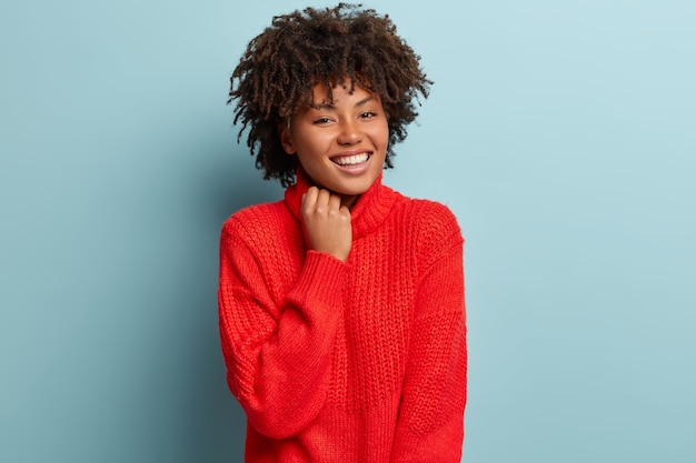 Mujer joven con corte de pelo afro vistiendo suéter rojo