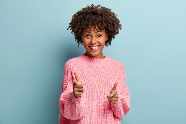 Mujer joven con corte de pelo afro vistiendo suéter rosa