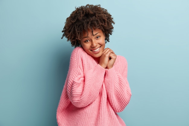 Mujer joven con corte de pelo afro vistiendo suéter rosa