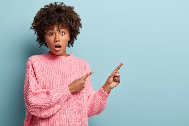 Mujer joven con corte de pelo afro vistiendo suéter rosa