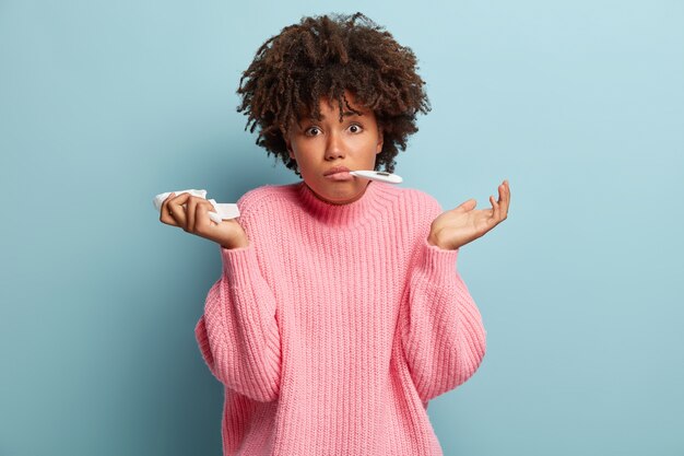 Mujer joven con corte de pelo afro vistiendo suéter rosa