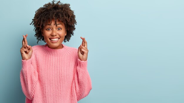 Mujer joven con corte de pelo afro vistiendo suéter rosa