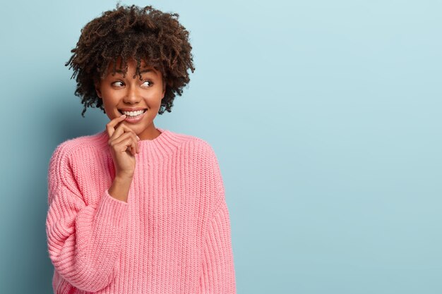 Mujer joven con corte de pelo afro vistiendo suéter rosa