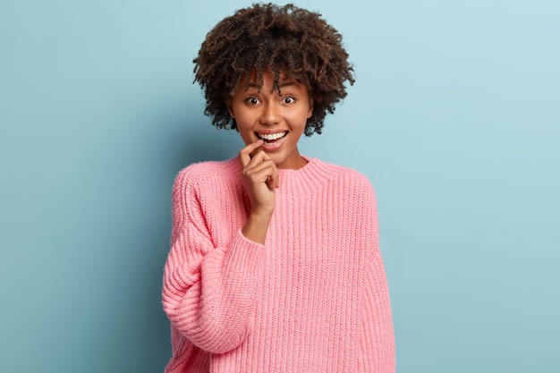 Mujer joven con corte de pelo afro vistiendo suéter rosa