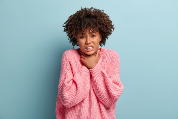 Mujer joven con corte de pelo afro vistiendo suéter rosa