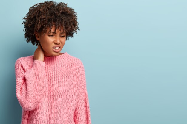 Mujer joven con corte de pelo afro vistiendo suéter rosa