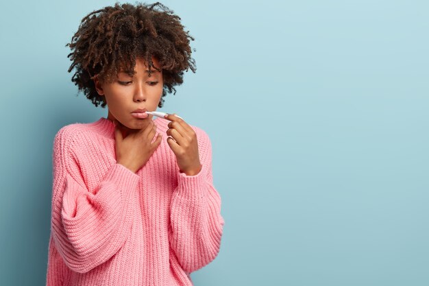 Mujer joven con corte de pelo afro vistiendo suéter rosa