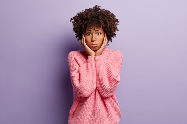 Mujer joven con corte de pelo afro vistiendo suéter rosa