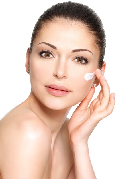 Mujer joven con crema cosmética en un rostro limpio y fresco. Concepto de cuidado de la piel