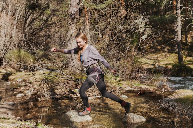 Mujer joven cruzando un río