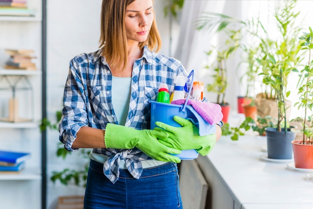 Mujer joven con cubo de equipos de limpieza