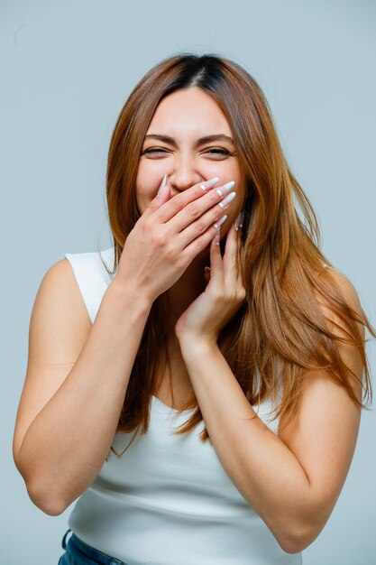 Mujer joven cubriendo la boca con la mano mientras se reía