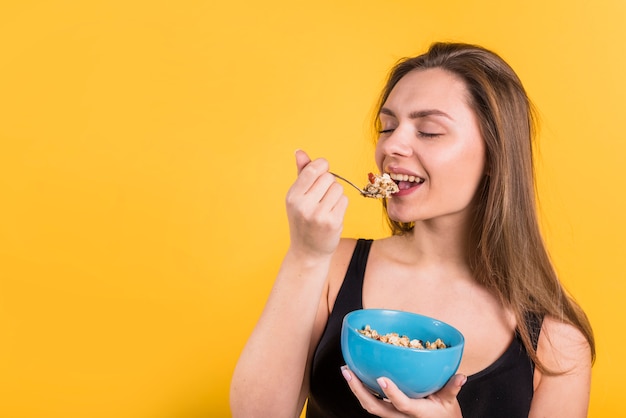 Mujer joven con cuchara y tazón comiendo escamas