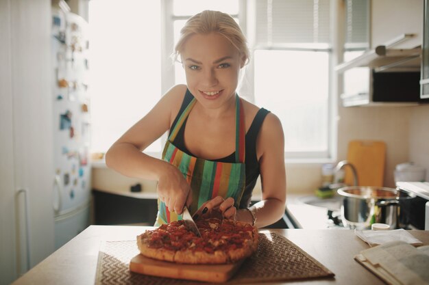 Mujer joven con un cuchillo corta la pizza