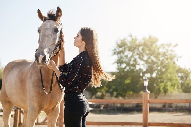 Mujer joven cuidando un caballo en una granja dirigida por su abuelo Pronto se convertirá en administradora de sementales