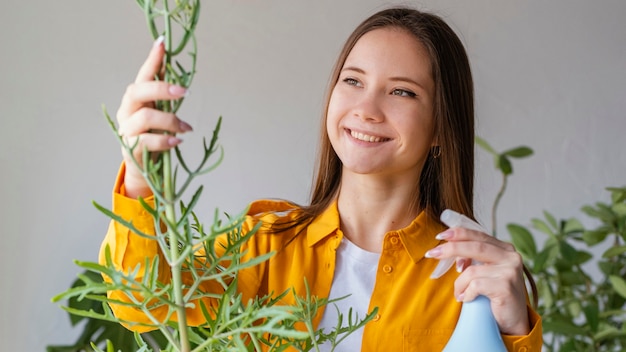 Foto gratuita mujer joven cuidando sus plantas en casa