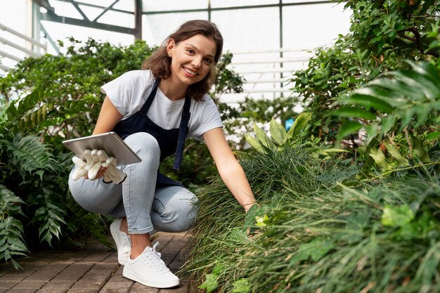 Mujer joven cuidando sus plantas en invernadero