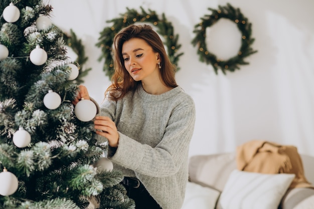 Mujer joven decorar el árbol de navidad