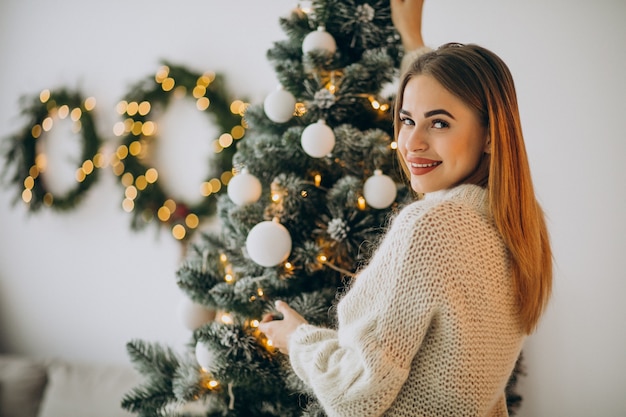 Mujer joven decorar el árbol de navidad
