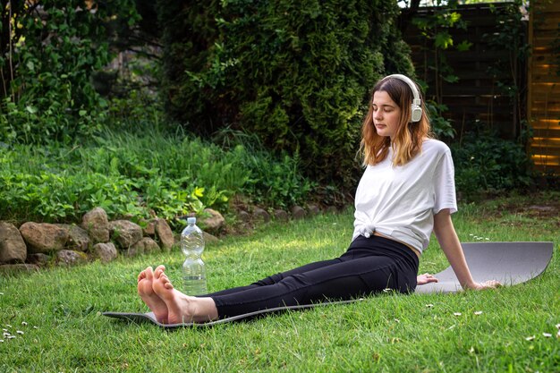 Una mujer joven se dedica a la aptitud en la naturaleza en una alfombra