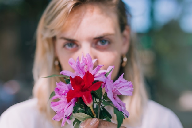 Mujer joven Defocused con ramo de flores delante de su boca