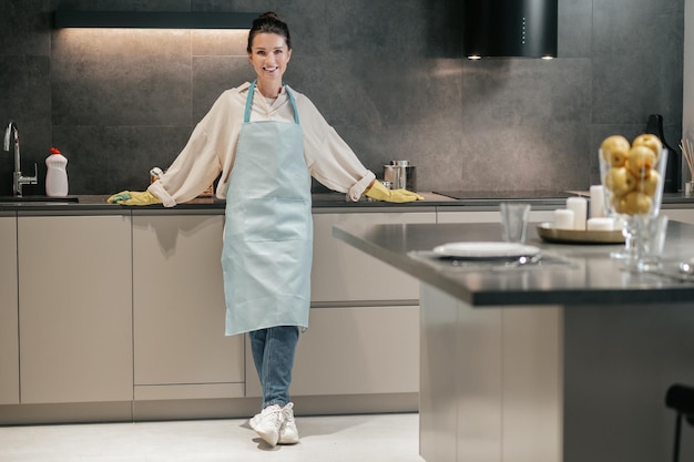 Mujer joven en delantal y guantes en la cocina.