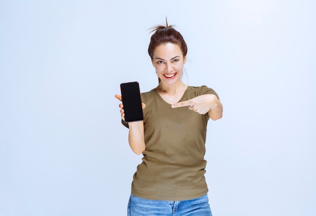 Mujer joven demostrando su nuevo modelo de smartphone negro