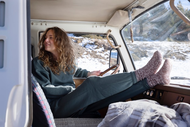 Mujer joven dentro de una autocaravana durante el viaje de invierno