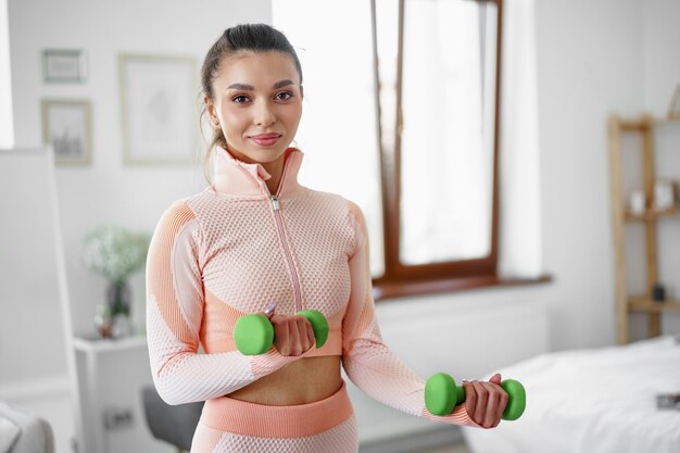 Mujer joven deportiva haciendo ejercicio en casa con pesas