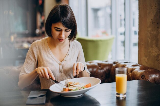 Mujer joven desayunando saludablemente con jugo en un café