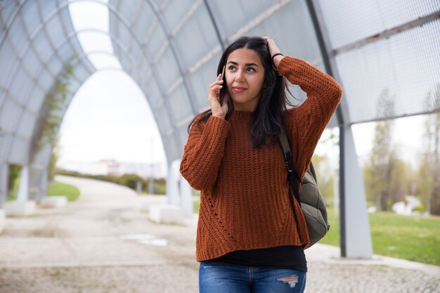 Mujer joven desconcertada que habla en el teléfono celular