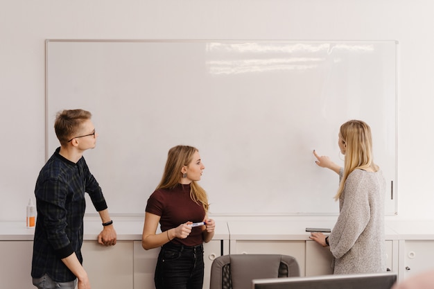 Mujer joven discutiendo con colegas sobre pizarra en la oficina