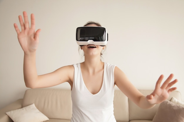 Mujer joven disfruta de juegos de realidad virtual en el sofá en casa