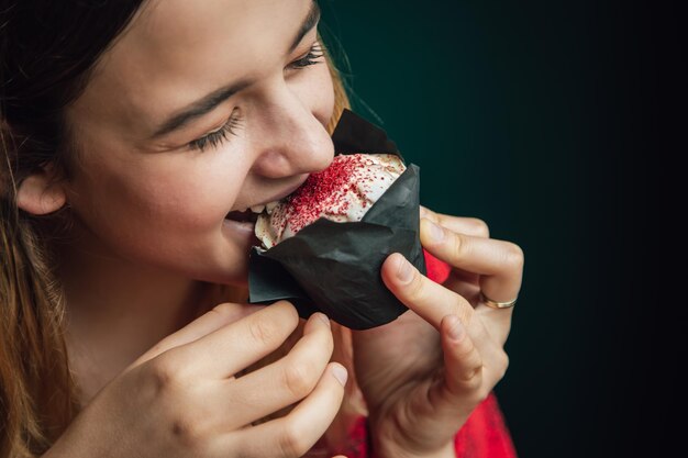 Una mujer joven disfruta de un muffin de frambuesa en un café.