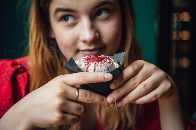 Una mujer joven disfruta de un muffin de frambuesa en un café.
