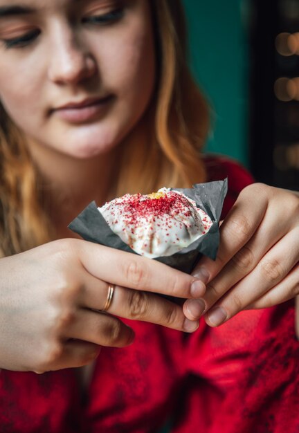 Una mujer joven disfruta de un muffin de frambuesa en un café.