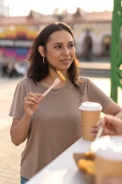 Mujer joven disfrutando de una deliciosa comida callejera