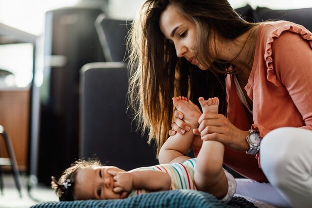 Mujer joven disfrutando del tiempo que está pasando con su linda niña en casa