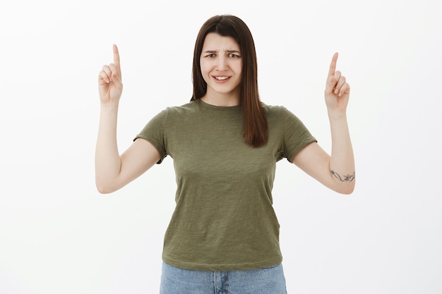 Mujer joven disgustada y decepcionada apuntando hacia arriba