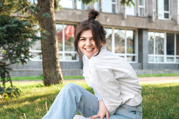 Mujer joven divertida con un moño en la cabeza en un parque de la ciudad