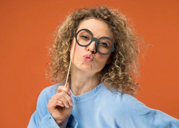 Mujer joven divirtiéndose con gafas falsas