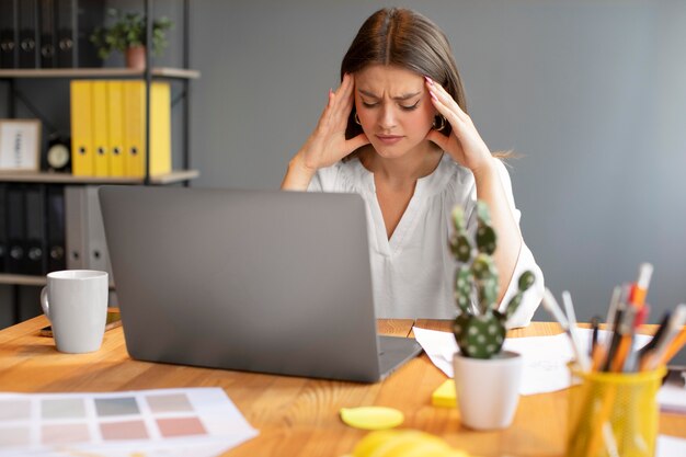 Mujer joven con dolor de cabeza en el trabajo