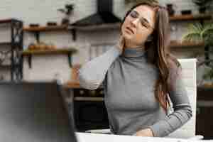 Foto gratuita mujer joven con dolor de cuello mientras trabaja desde casa