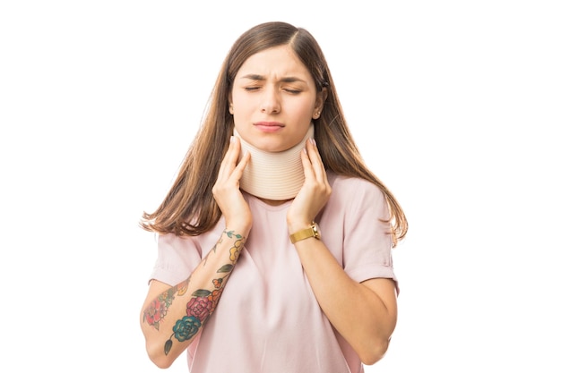 mujer joven, en, dolor, llevando, collarín cervical, encima, fondo blanco