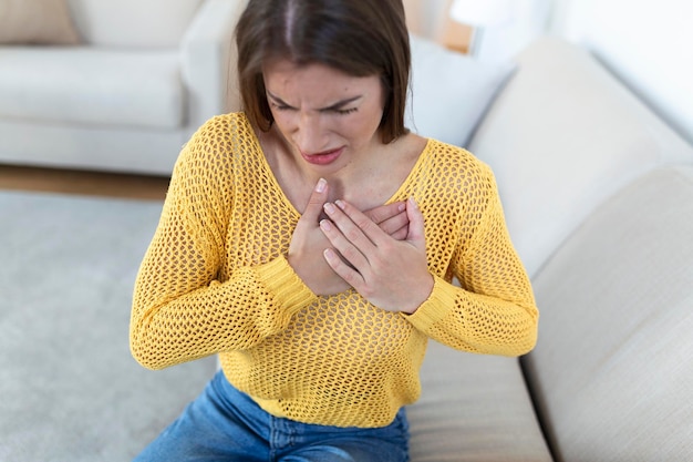 Mujer joven con dolor de pecho Dolor agudo posible ataque al corazón Efecto del estrés y el concepto de estilo de vida poco saludable