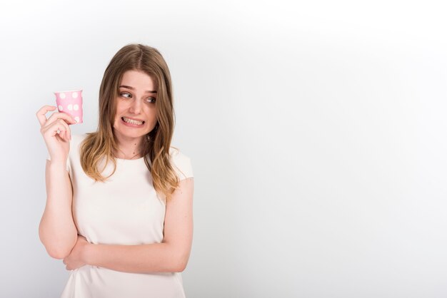 Mujer joven dudosa con vaso de papel